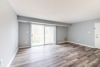 A room with a sliding glass door and wooden flooring at BellaVista Apartments in Woodbridge, VA